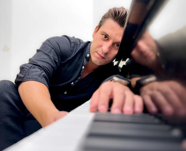 Amaç Erdem beside a piano